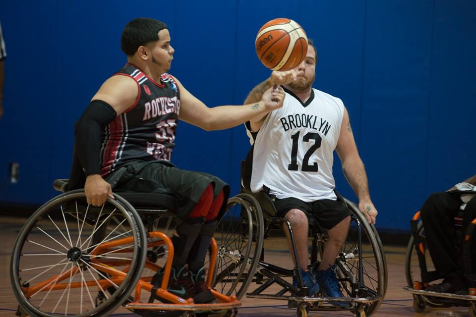 Two wheelchair athletes compete for a loose basketball