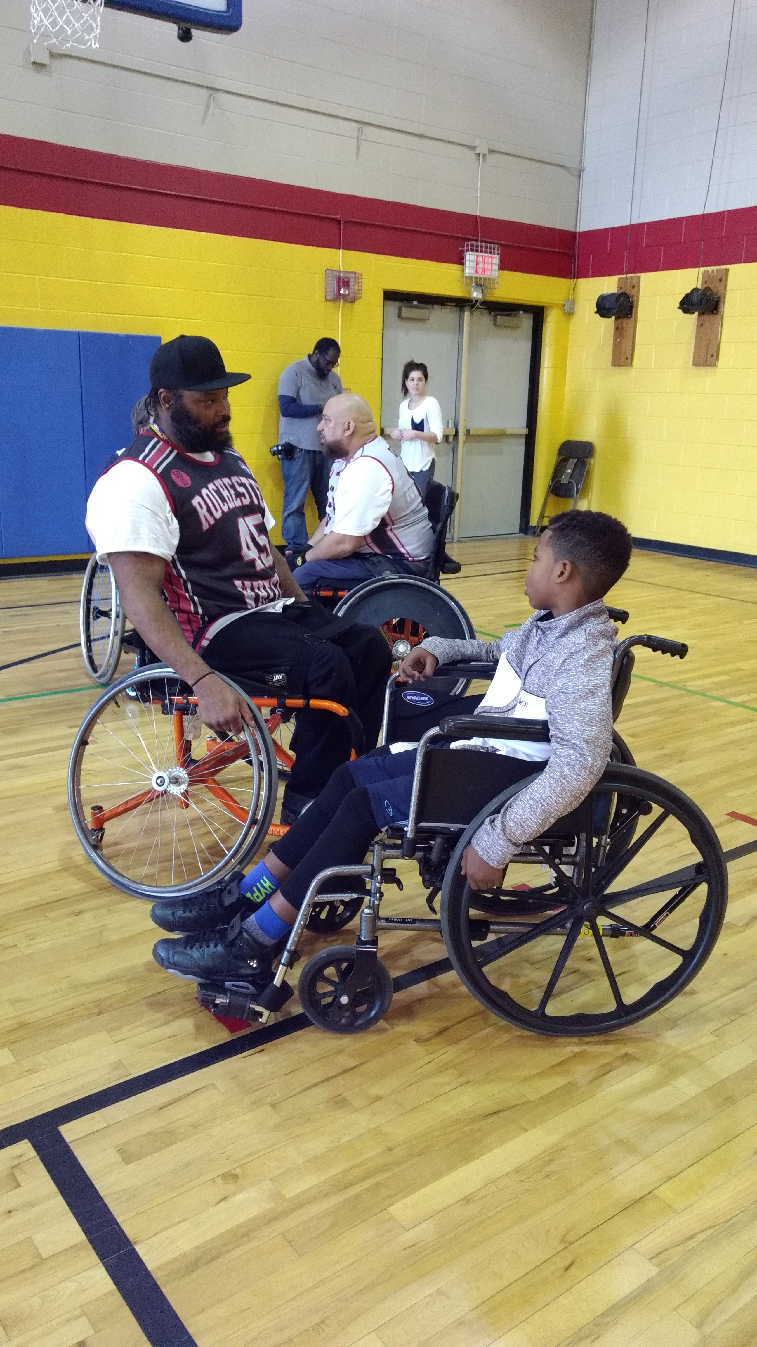 Wheelchair basketball player talks with youth in a manual chair about the game of wheelchair basketball