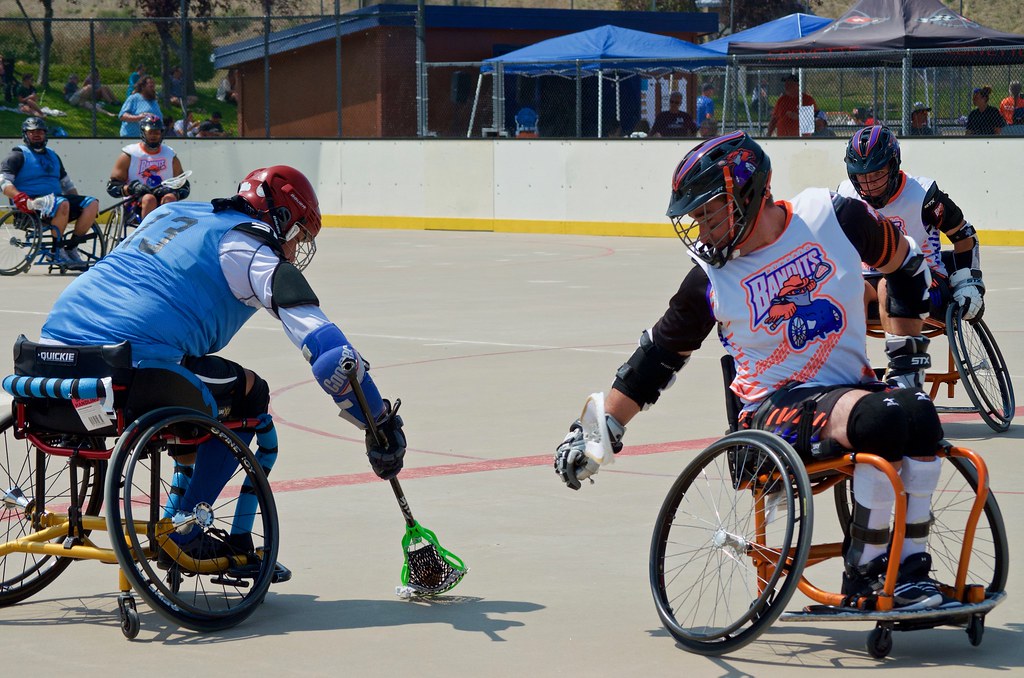 Wheelchair Lacross players grapple for ball on outdoor lacross field