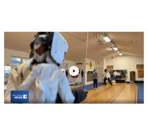 Screenshot of a Spectrum News story showing fencers in the gym at Ludus Fencing Studio.