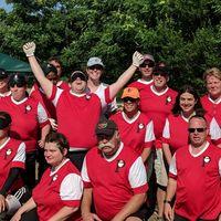 group of 12+ people in red jerseys with white sleeves, one person with both arms raised in victory