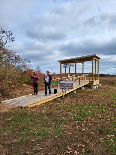 A new wooden ramp leads to an open air viewing platform with a roof for shade and two people stand on the ramp at opening day
