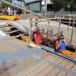 Two people in a kayak on an adaptive kayak launch ready to move out into the water