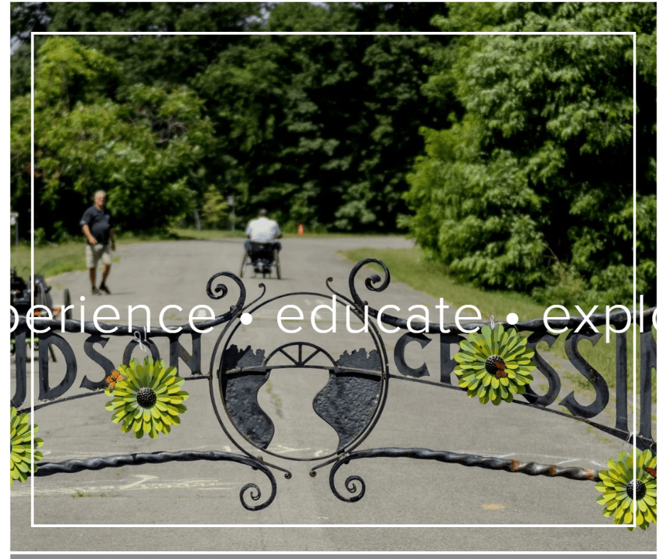 A screenshot of Hudson Crossing Park's website showing the wrought iron gate at their entrance with "Hudson Crossing Park" and a wide paved pathway in the background with a person walking and another person cycling using a handcycle