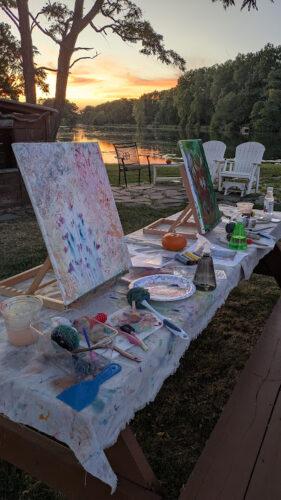 An outdoor art studio set up along the Erie Canalway with easels and painting supplies on the tables