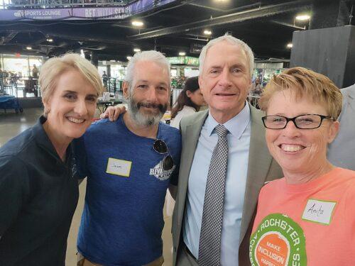 Two women on either side of two men, one who is wearing a suit and tie and is the mayor of Buffalo; in an airy arena.
