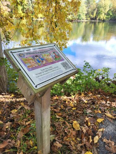 A wayfinding sign is beside an overlook onto the canal and blue sky is reflecting on the water